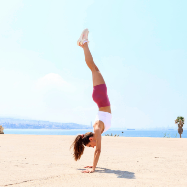 Nicole Nahed doing a handstand on the beach.