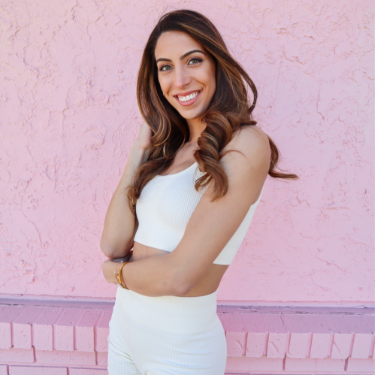 Nicole Nahed posing behind a pink wall.